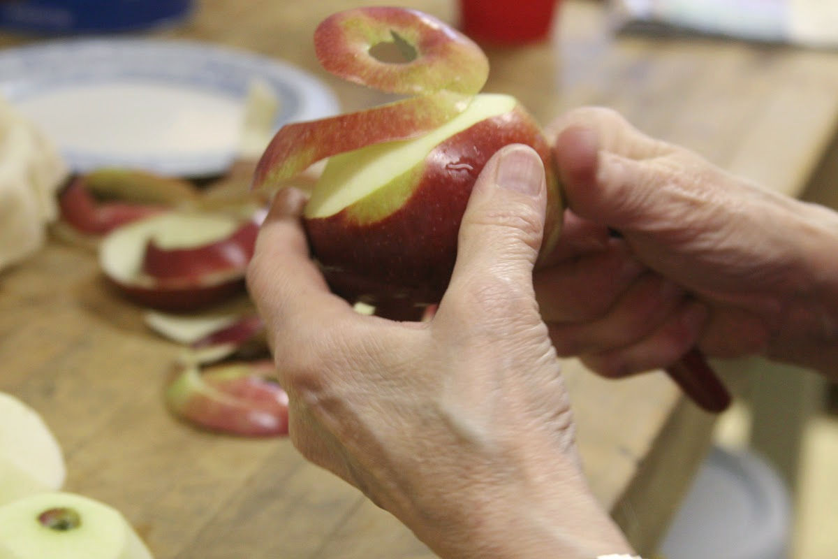 Hand peeling apples over butcher block.