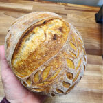 Small sourdough loaf held by hand.