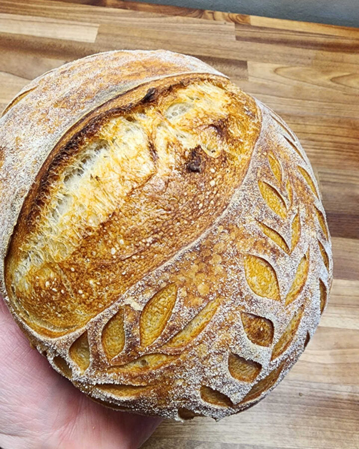 Small sourdough loaf held by hand.