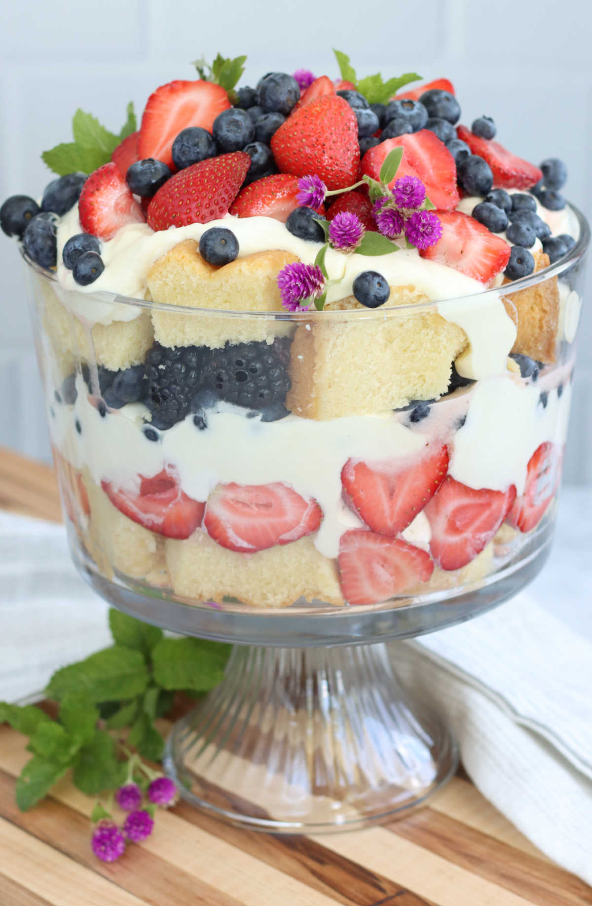 Trifle with layers of pound cake, pudding and berries in glass trifle dish.