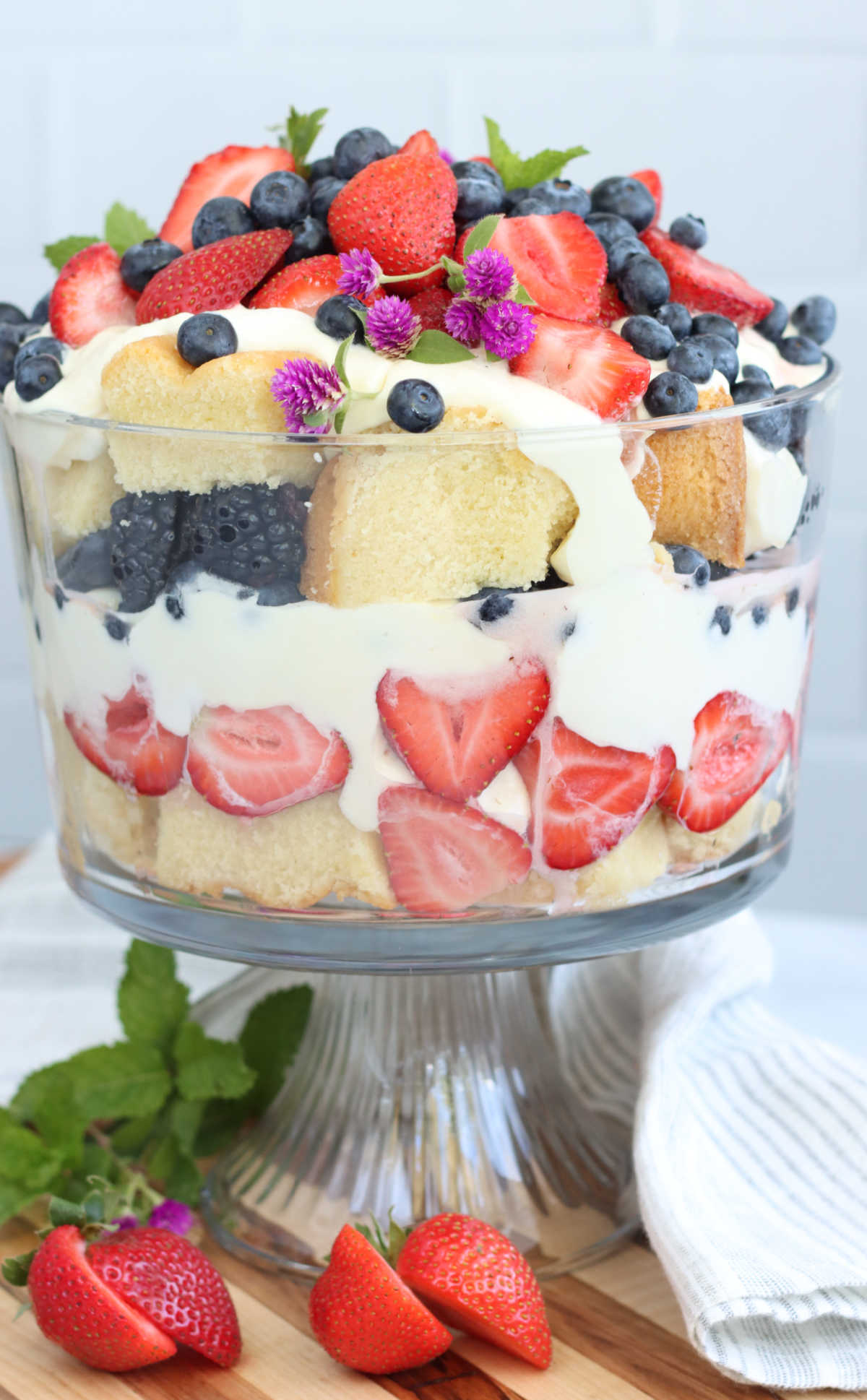 Berry trifle in glass footed trifle dish, layers of pudding, cake and berries.