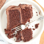 Slice of chocolate cake on small white plate with vintage fork.