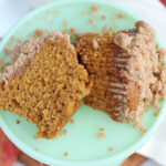 Close up of pumpkin crumb muffin cut in half on mint green cake dish.