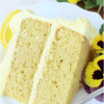 Slice of lemon layer cake on small white plate with fork.