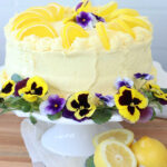 Lemon cake on white footed cake dish.