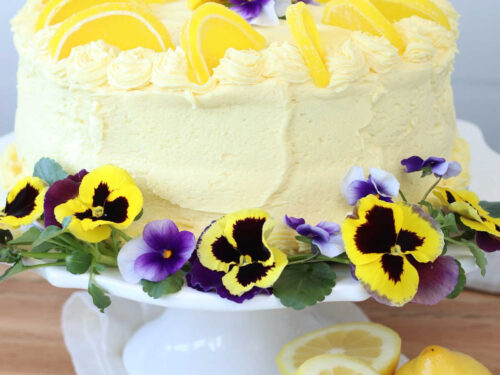 Lemon cake on white footed cake dish.