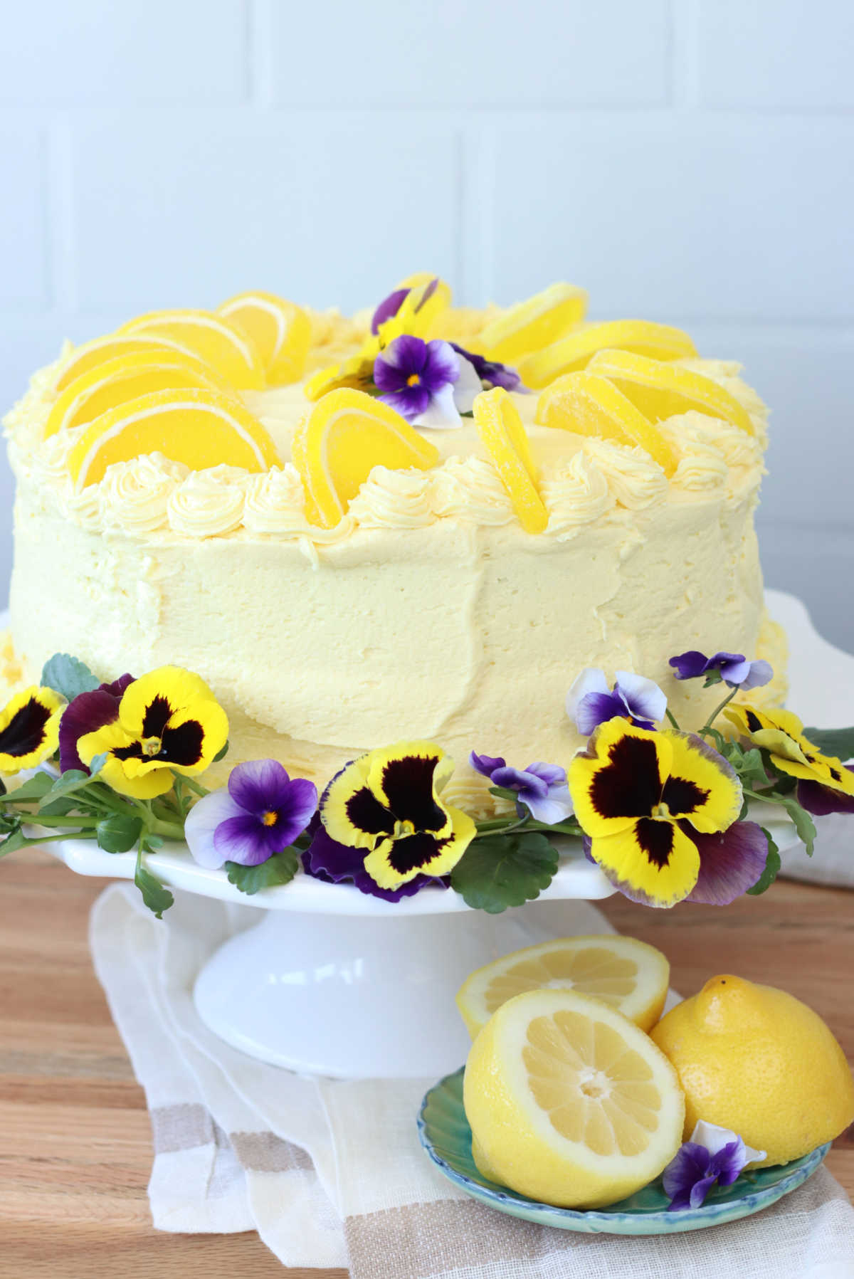 Lemon cake on white footed cake stand.