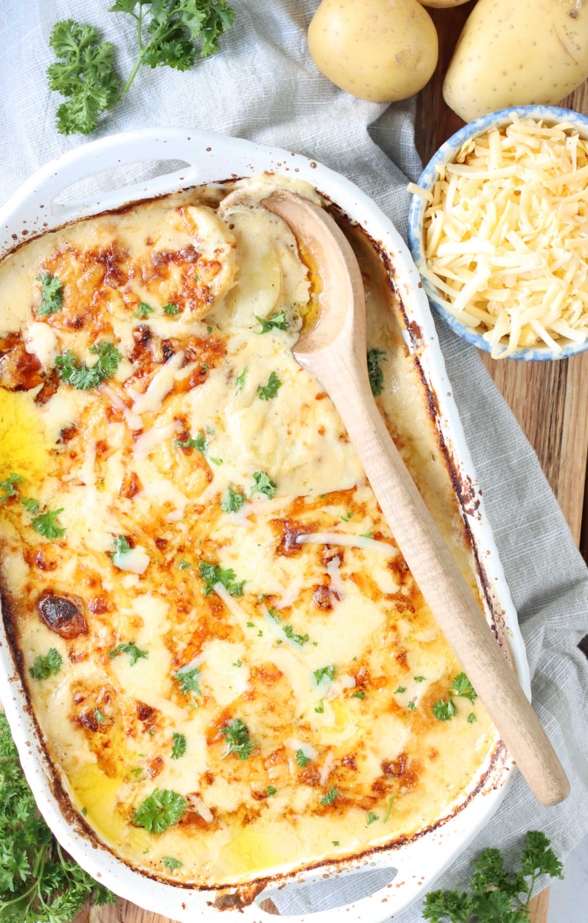 Au Gratin potatoes with browned crust on top in white baking dish.
