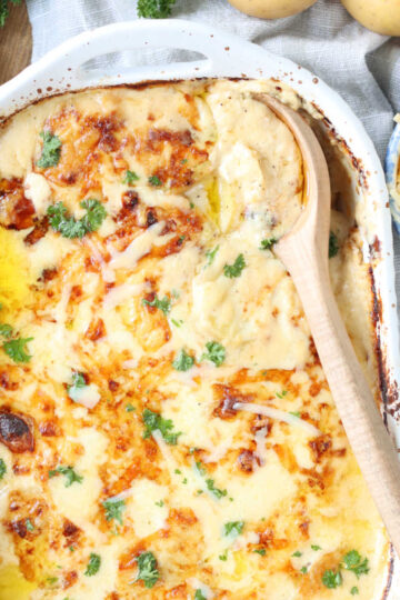 Scalloped potatoes baked in white baking dish.