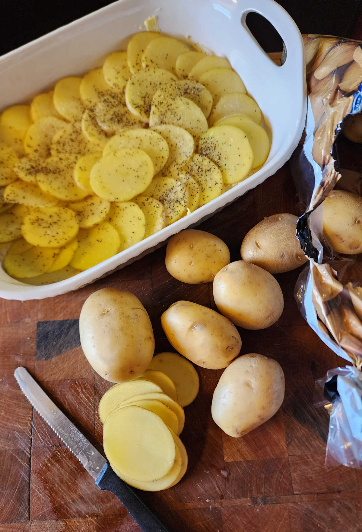 Layering potatoes in white ceramic baking dish.