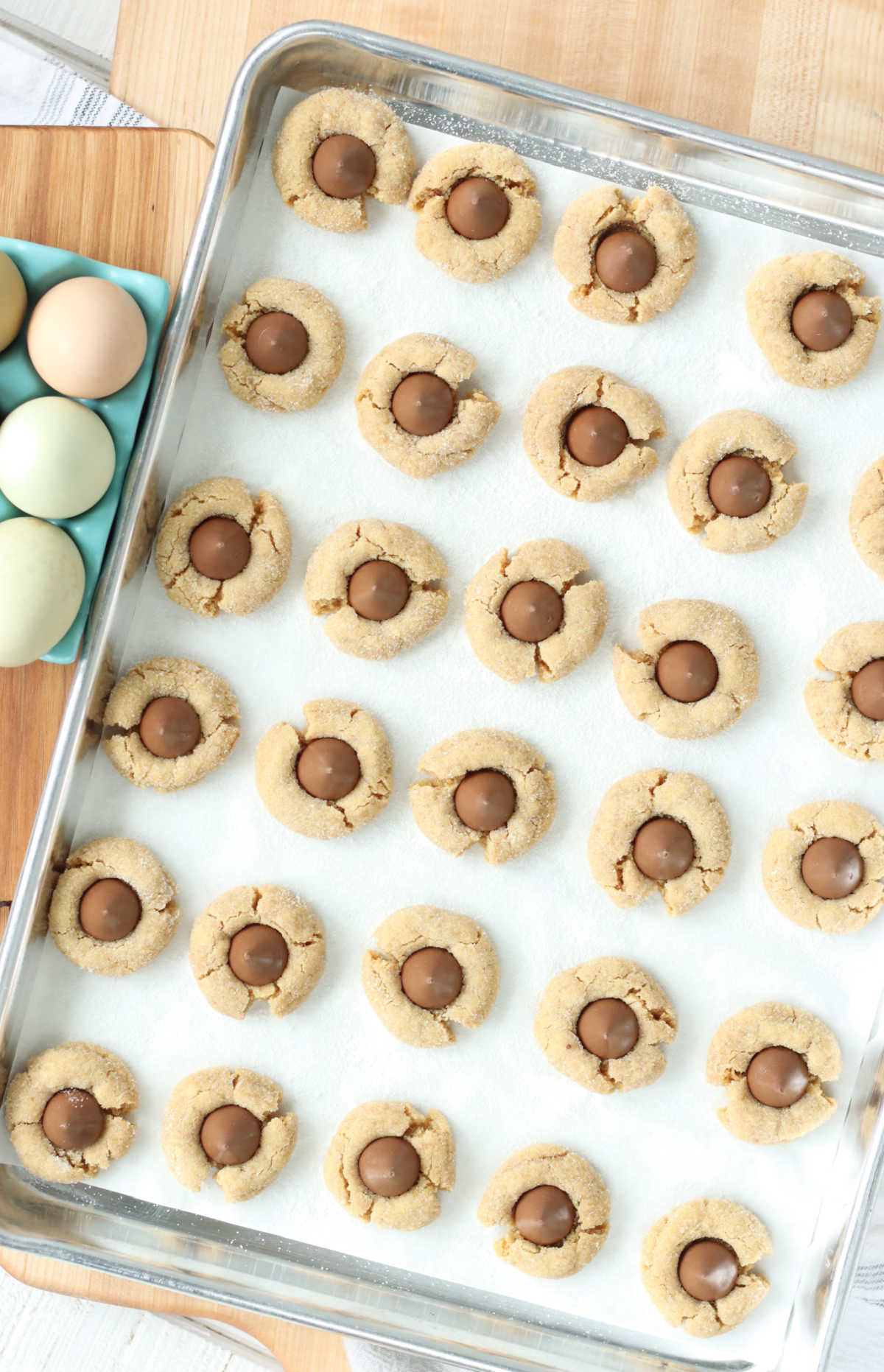 Peanut butter cookies with Hershey kiss centers on sheet pan.