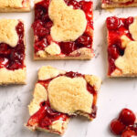 Cherry bars cut into squares on white marble counter.