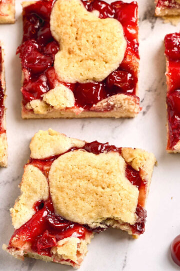 Cherry bars cut into squares on white marble counter.