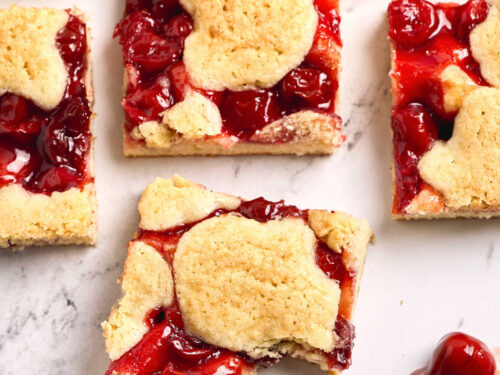 Cherry bars cut into squares on white marble counter.