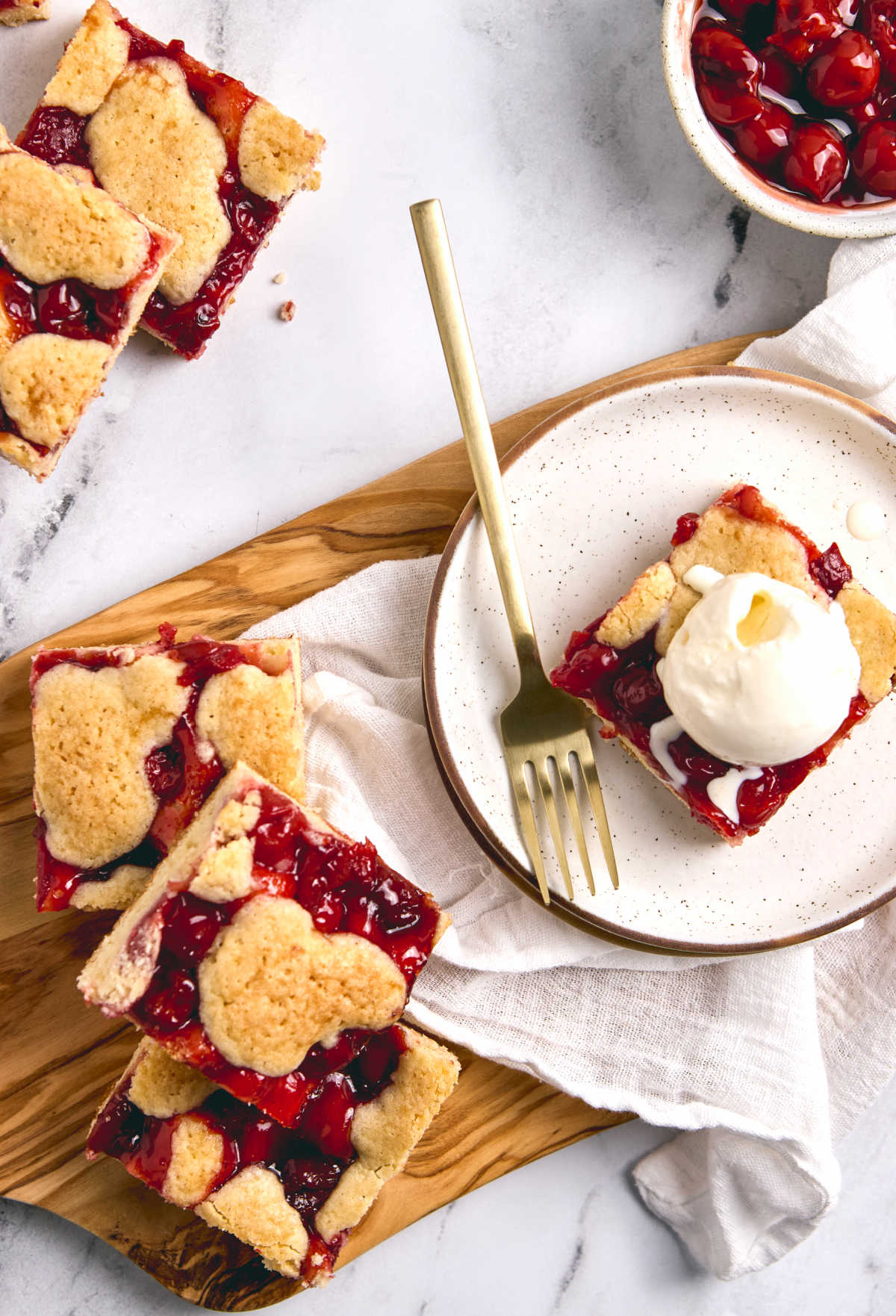 Cherry bars on wooden cutting board and small white plate.