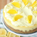 Closeup of lemon cheesecake on footed cake dish.