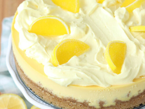 Closeup of lemon cheesecake on footed cake dish.