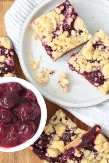 Cherry bar squares on small plate on wooden cutting board.