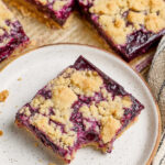 Close up of blueberry square on small white speckled plate.