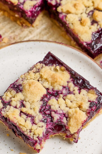 Close up of blueberry square on small white speckled plate.