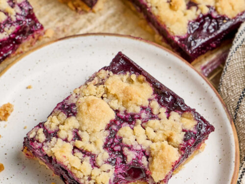 Close up of blueberry square on small white speckled plate.