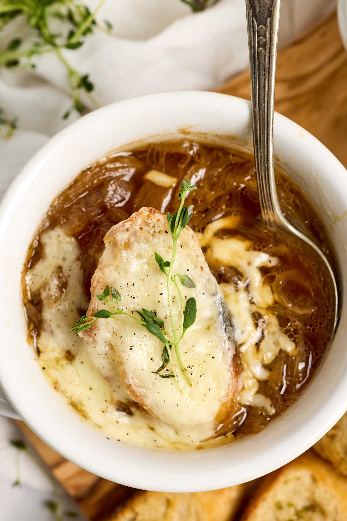 Closeup of bowl of French onion soup in white crock.