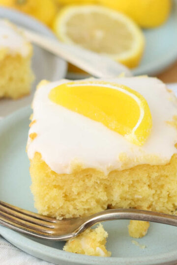 Square of lemon cake on small plate with Boston fruit slice on top.