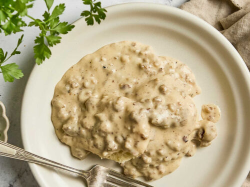 Biscuits and gravy on small white plate with fork.