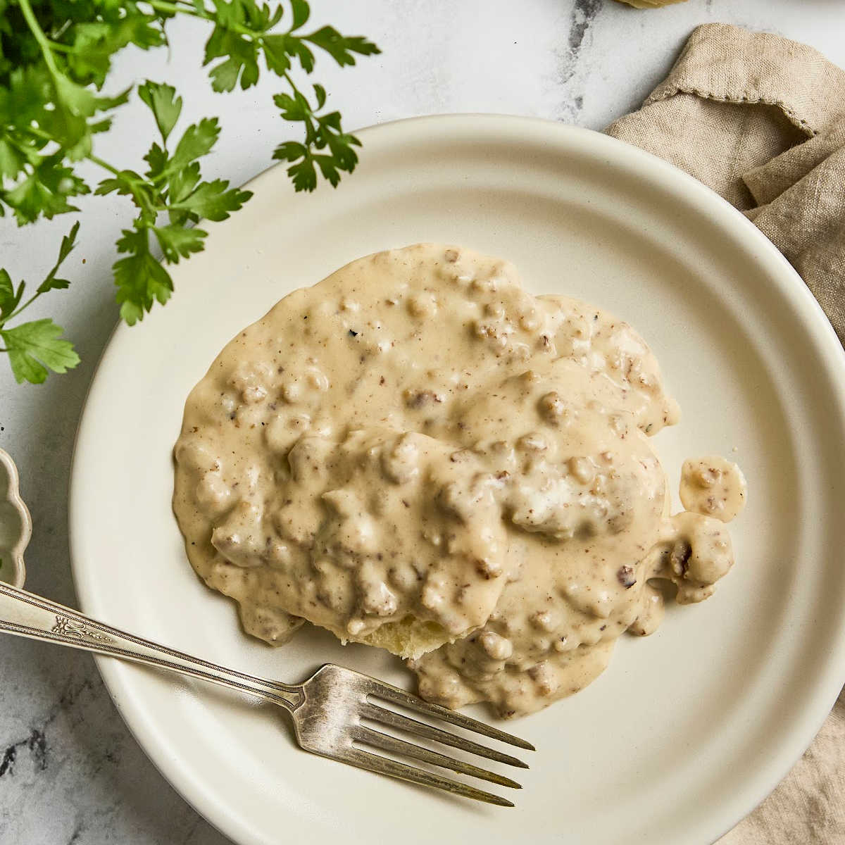 Biscuits and gravy on small white plate with fork.