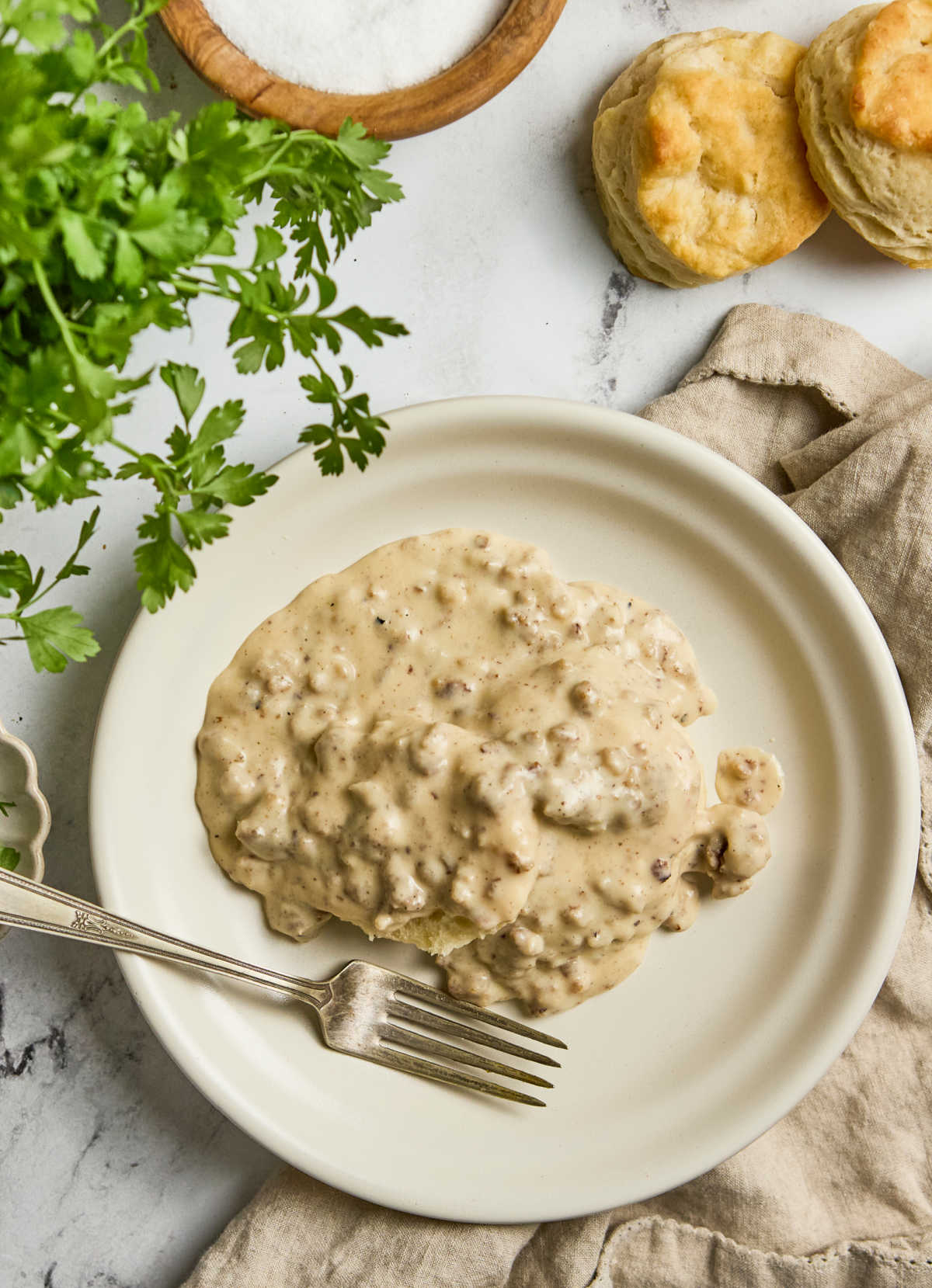 Plate with biscuit and sausage gravy, fork.