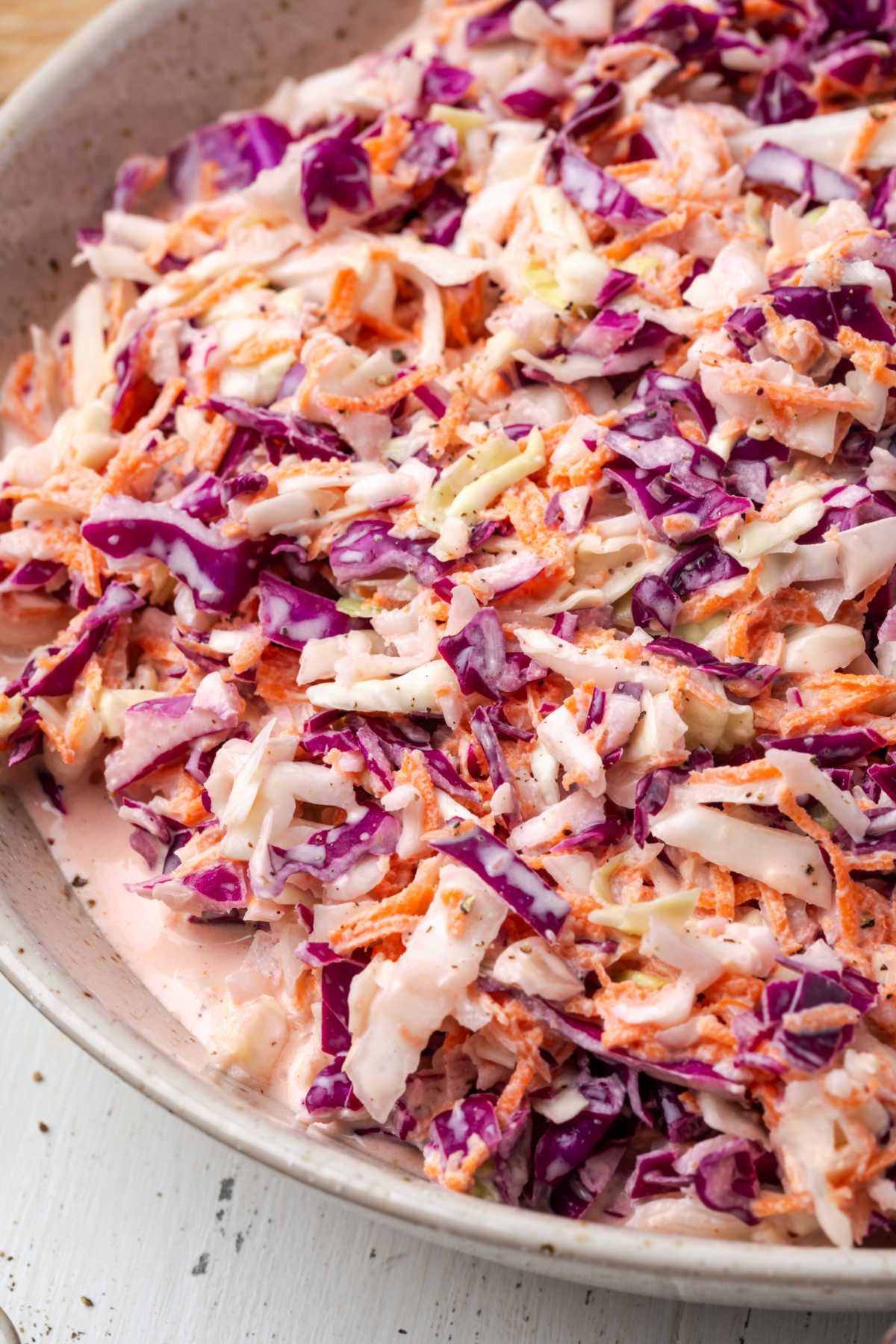 Coleslaw in white speckled bowl.