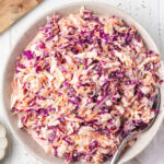 Coleslaw in bowl with serving spoon.