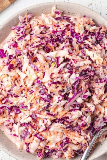 Coleslaw in bowl with serving spoon.