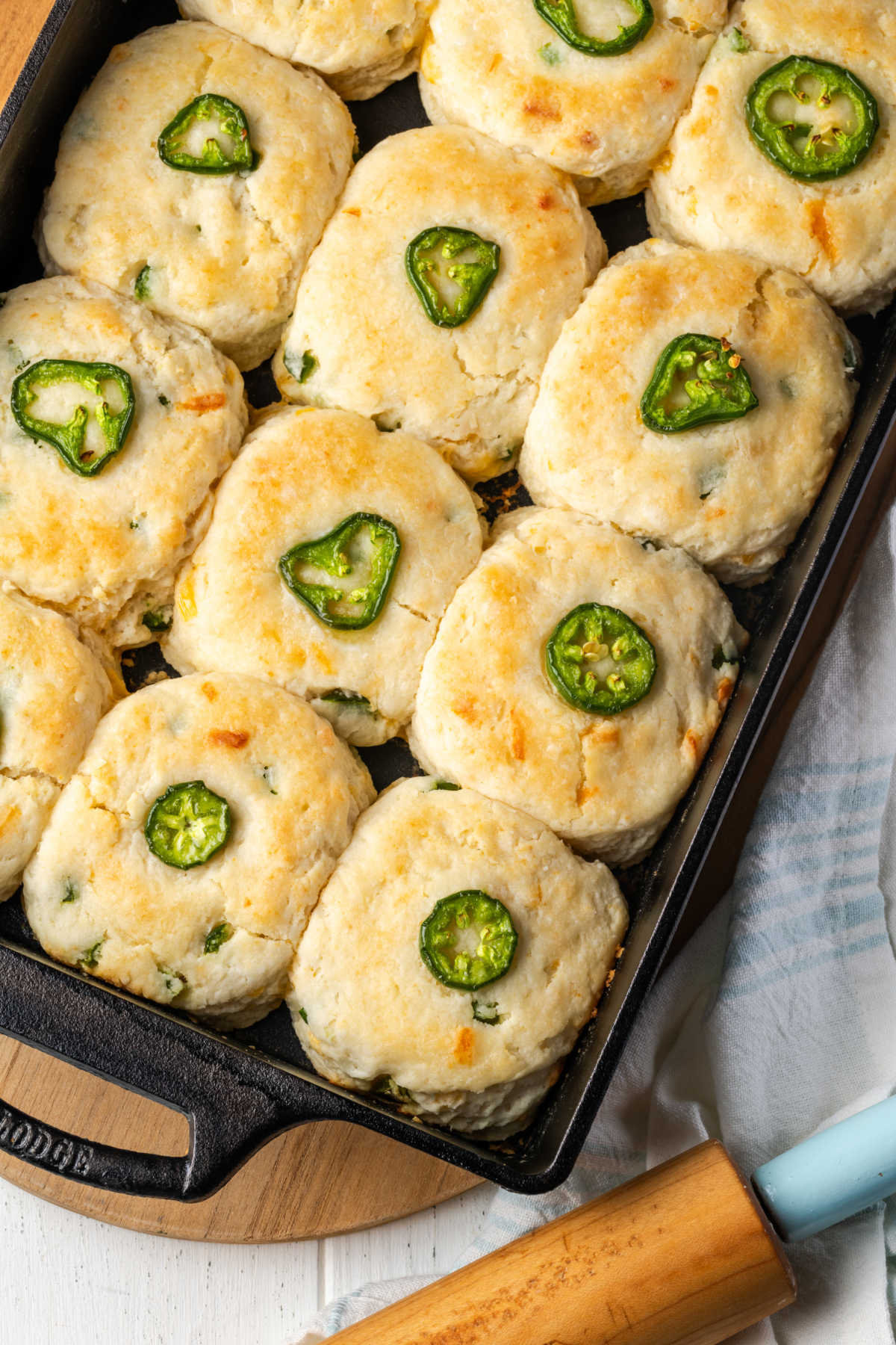 Close up of cheddar and jalapeno biscuits in cast iron baking pan on wood cutting board.