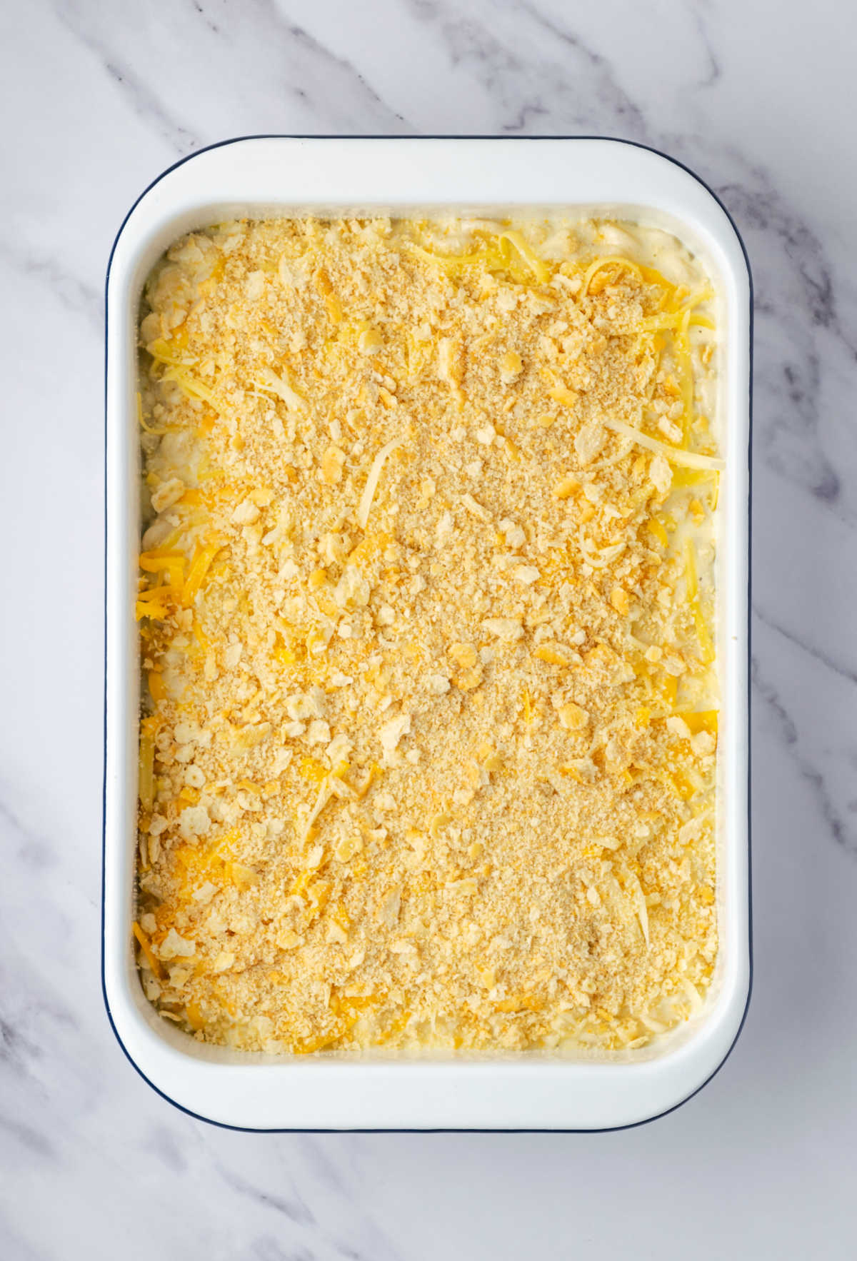 White casserole dish with macaroni, cheese and unbaked breadcrumb topping.