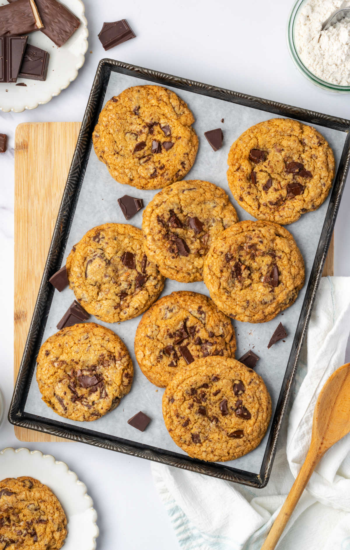 Chocolate chunk cookies on half sheet pan on wooden cutting board.