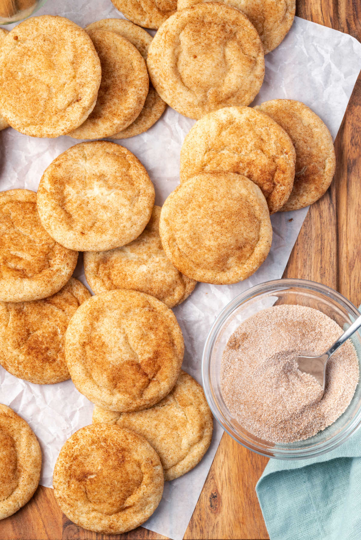 Snickerdoodle cookies on cutting board, cinnamon sugar in clear glass bowl with spoon.