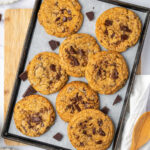 Chocolate chunk cookies on half sheet pan with chocolate pieces.
