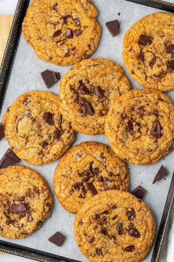 Chocolate chunk cookies on half sheet pan with chocolate pieces.