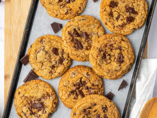 Chocolate chunk cookies on half sheet pan with chocolate pieces.