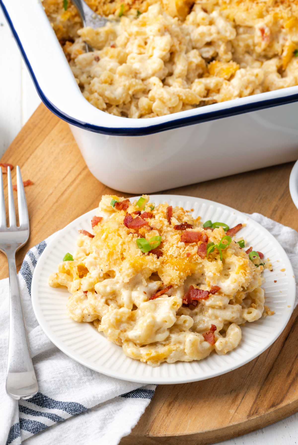Mac and cheese with breadcrumb topping, bacon, green onion, fork on small white plate.
