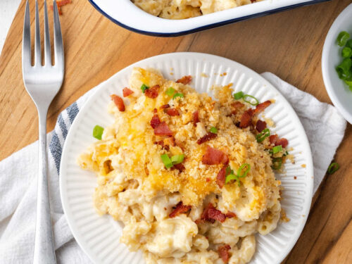 Baked mac and cheese, breadcrumb topping, bacon, green onion on small white plate with fork.