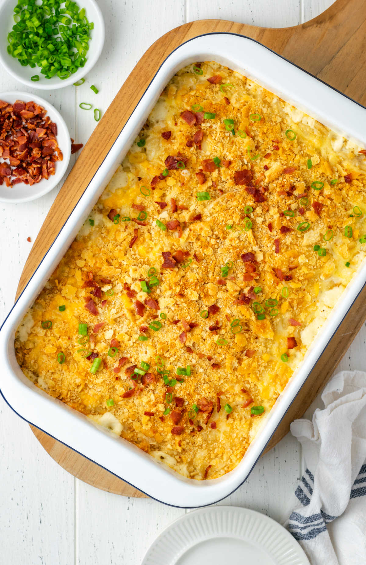 Baked mac and cheese in white casserole dish, bacon pieces and green onions.
