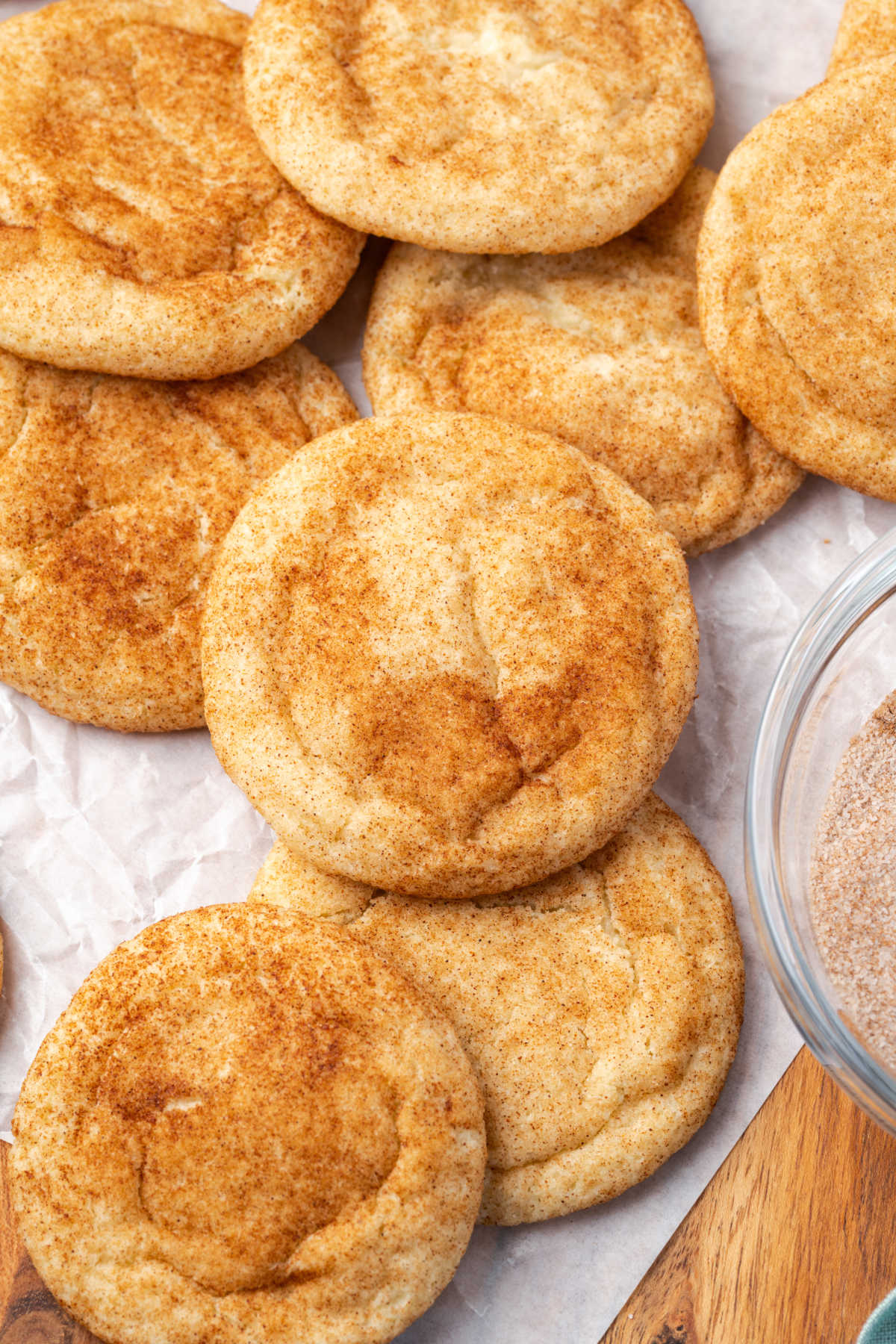 Cookies coated in cinnamon sugar on white parchment.