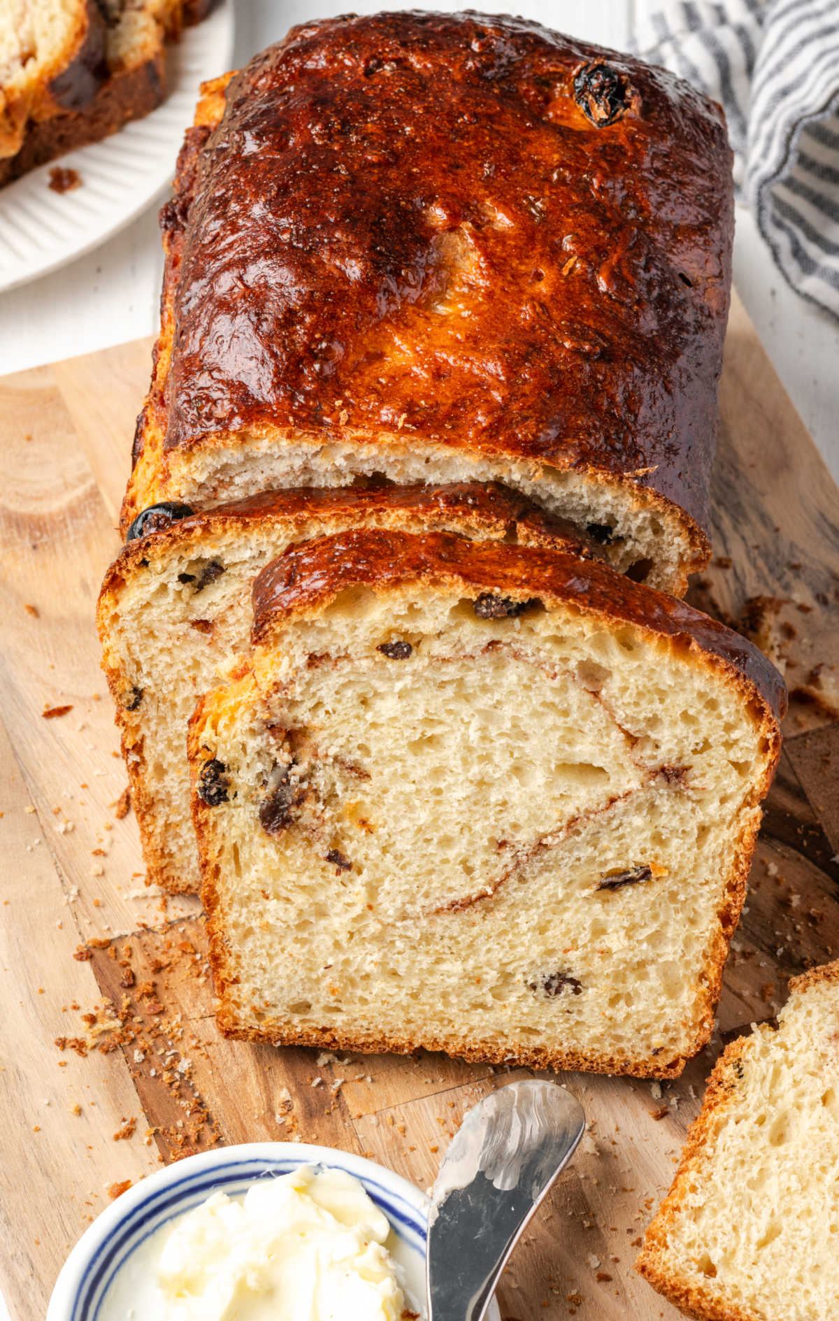 Cinnamon raisin bread partially sliced on cutting board.
