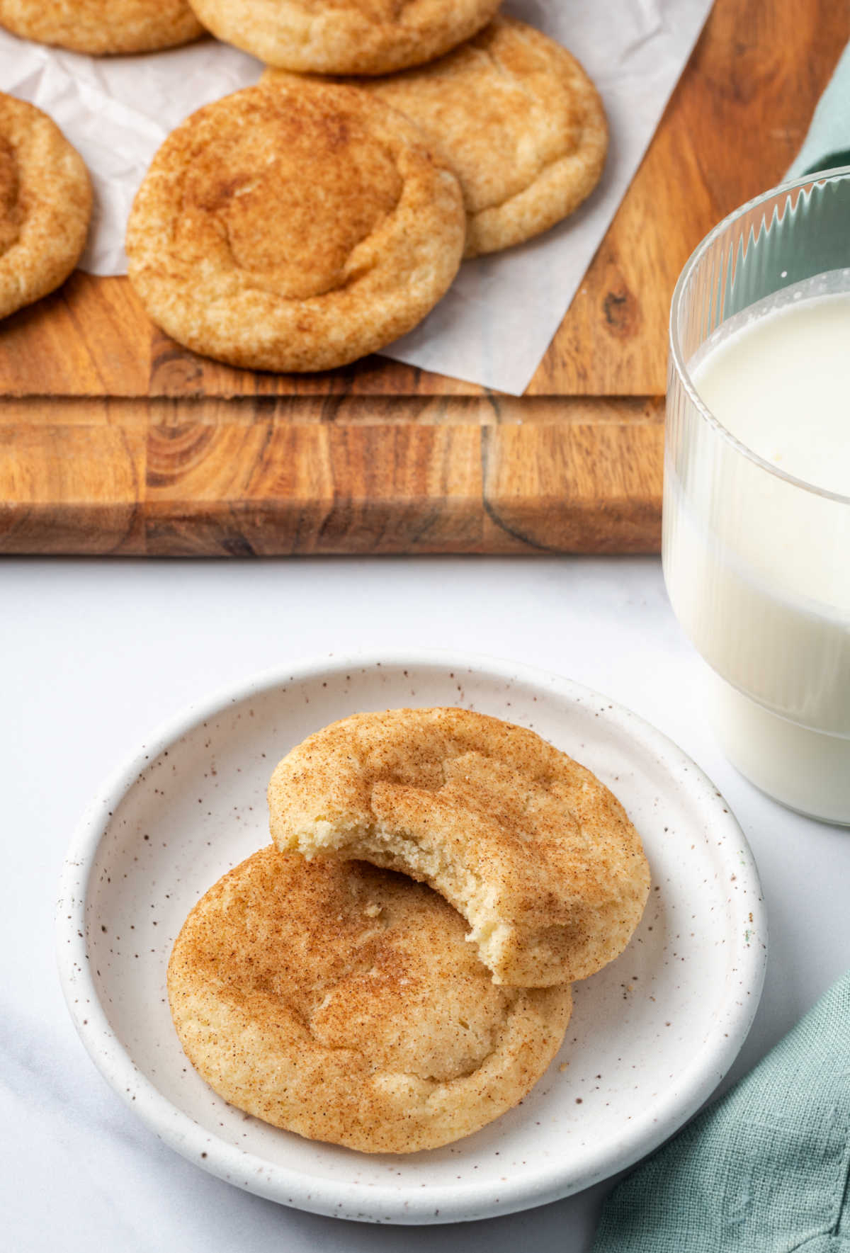 Two cookies on white speckled plate, one with bite out of it.