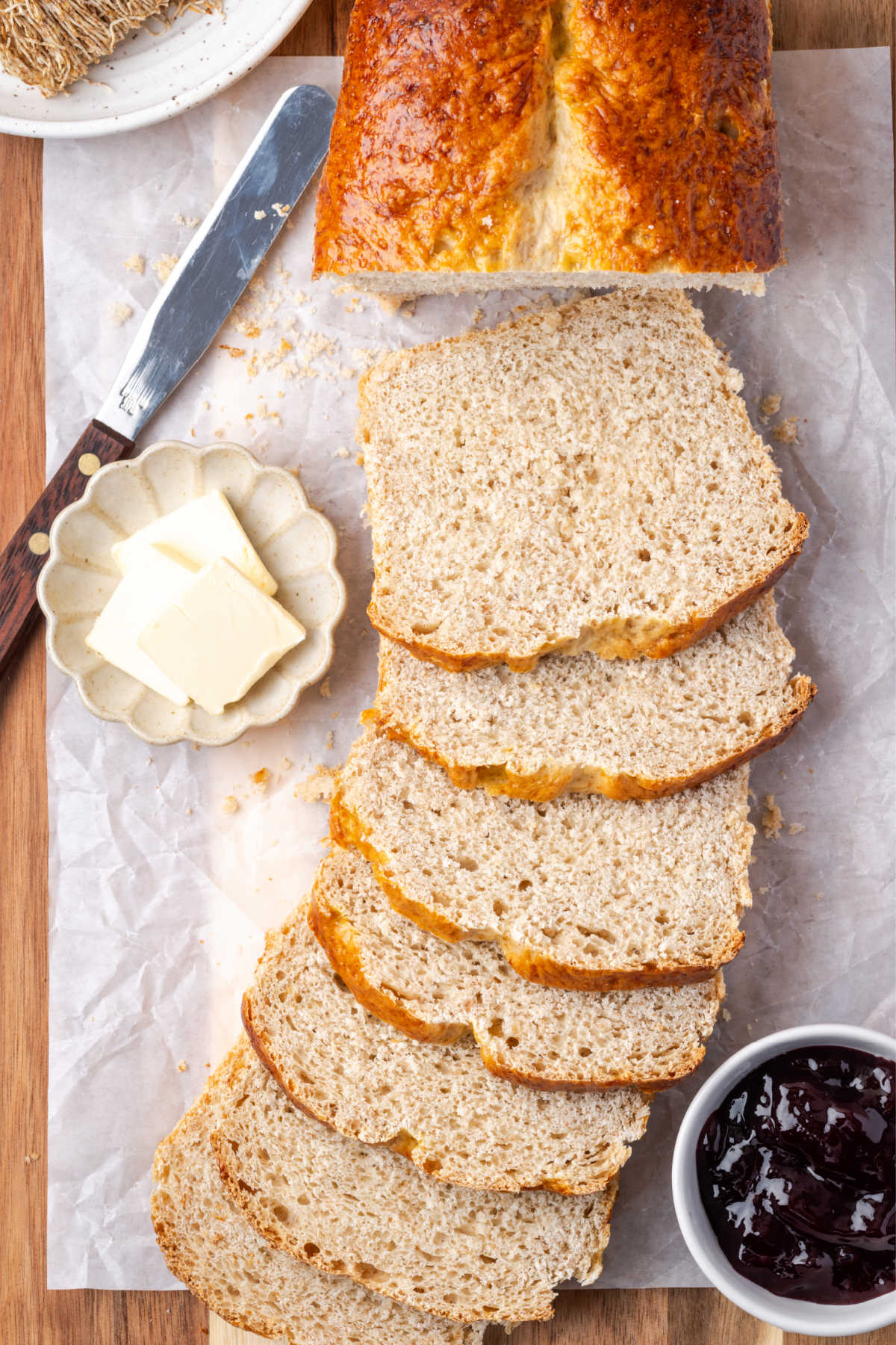 Sliced shredded wheat bread on cutting board, pads of butter on small plate.