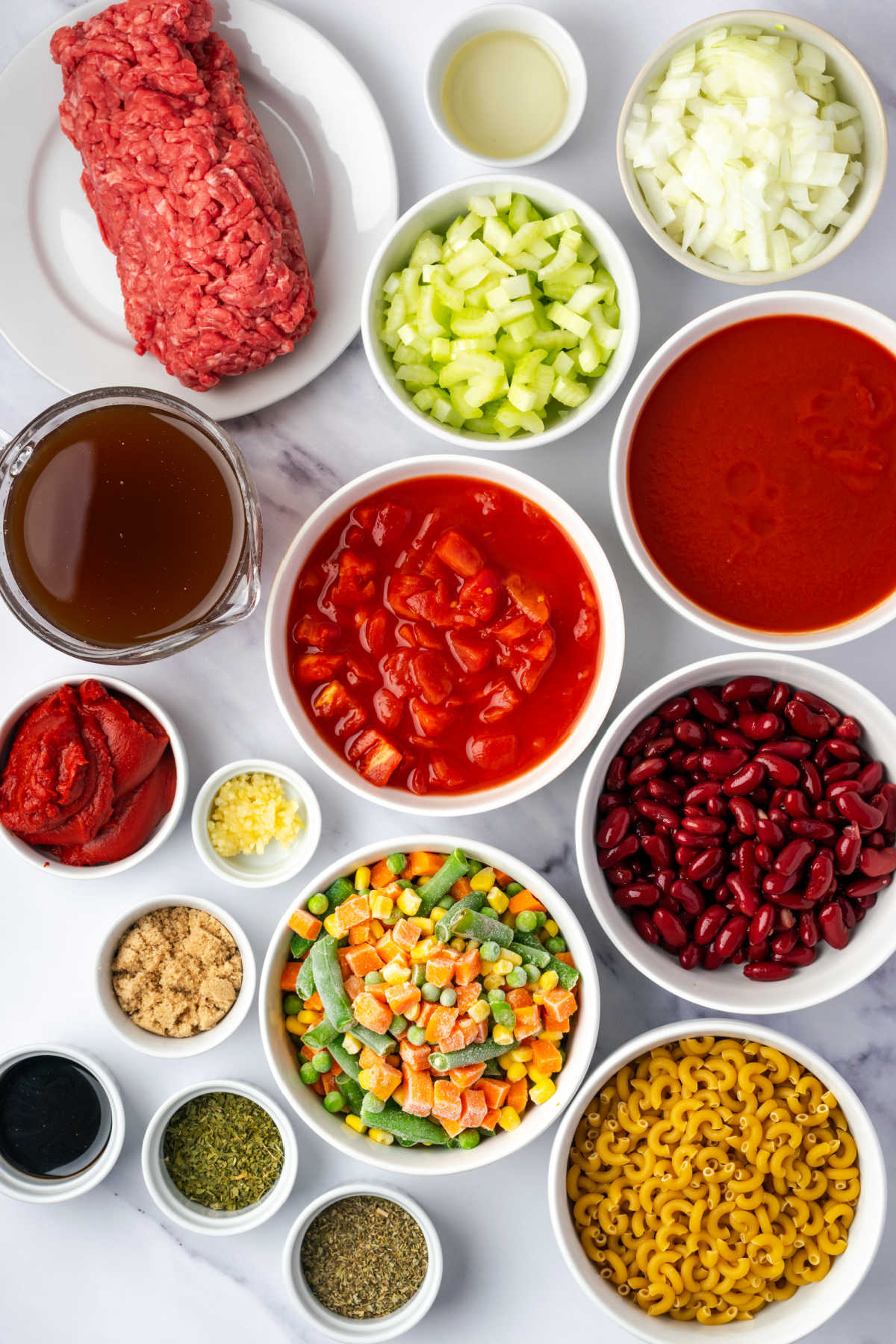 Ingredients in small white bowls for soup with ground beef.