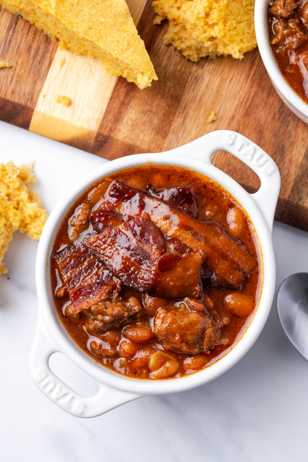 Baked beans with hamburger in white crock.