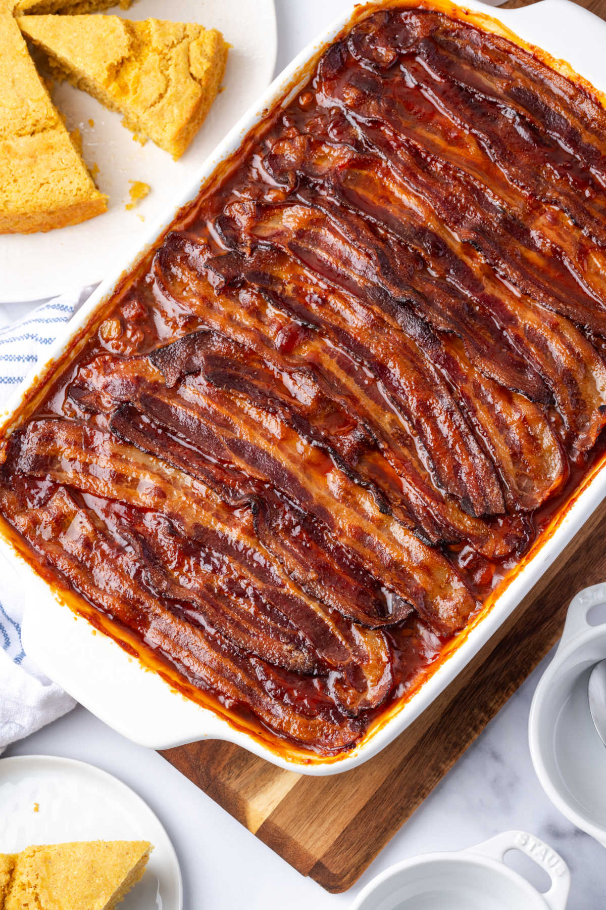Baked beans in white baking dish topped with bacon.